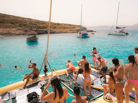 The catamaran anchored at a calm bay for swimming near Comino